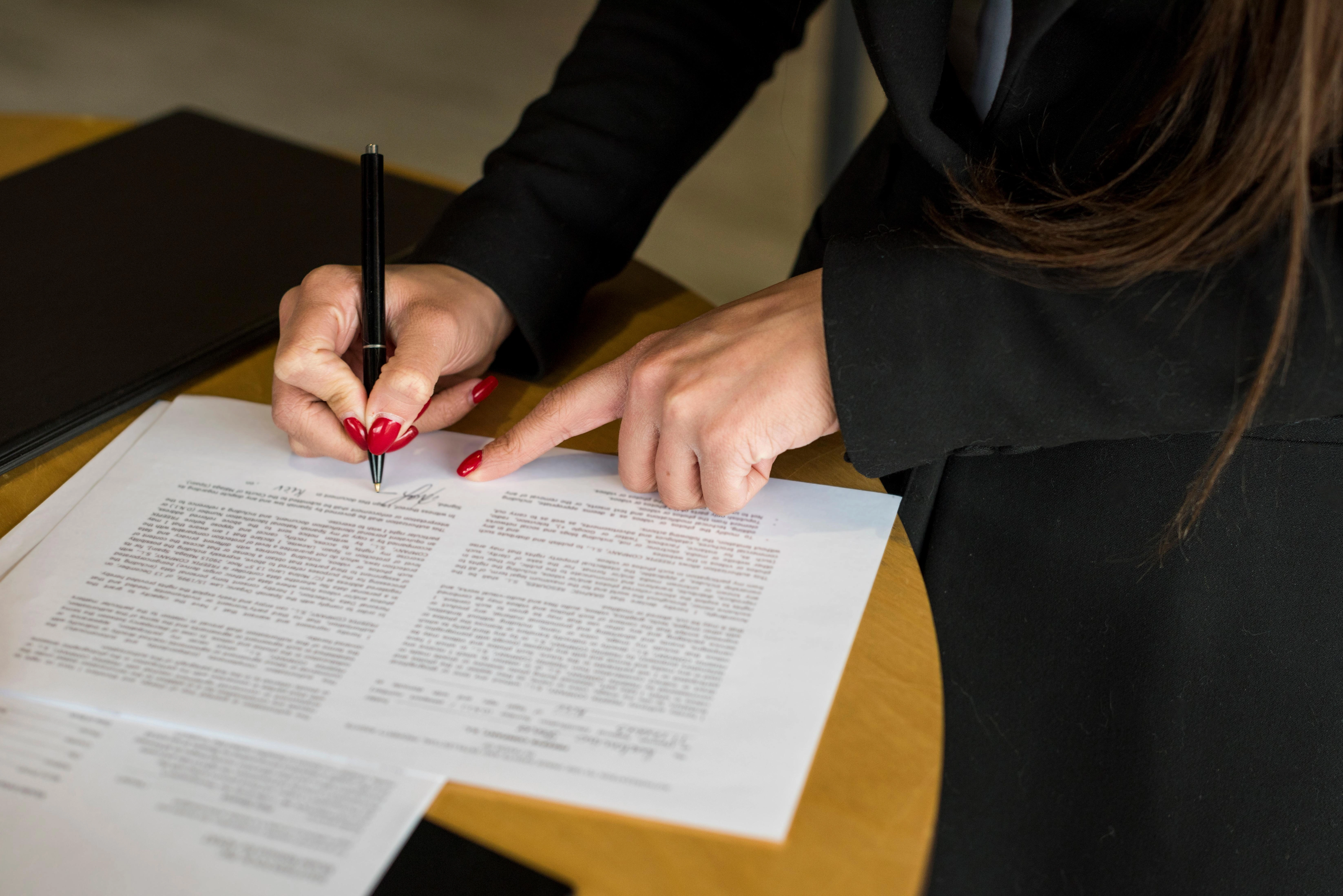 mulher executiva assinando documento com uma caneta preta